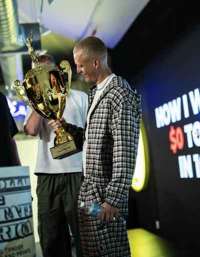 Sam Arch holding a $1M-a-month award trophy
